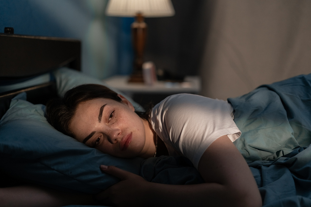 Erschöpfte junge Frau im Bett.